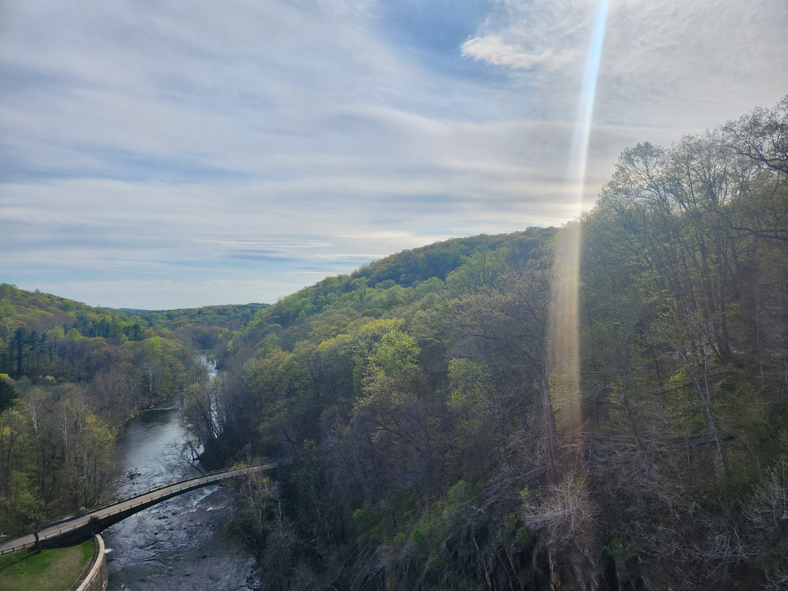 Sweeping view of the New Croton Dam spillway and surrounding hills under a clear blue April sky